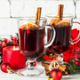 Glühwein im Glasbecher mit Frucht und Gewürzen auf Weiß