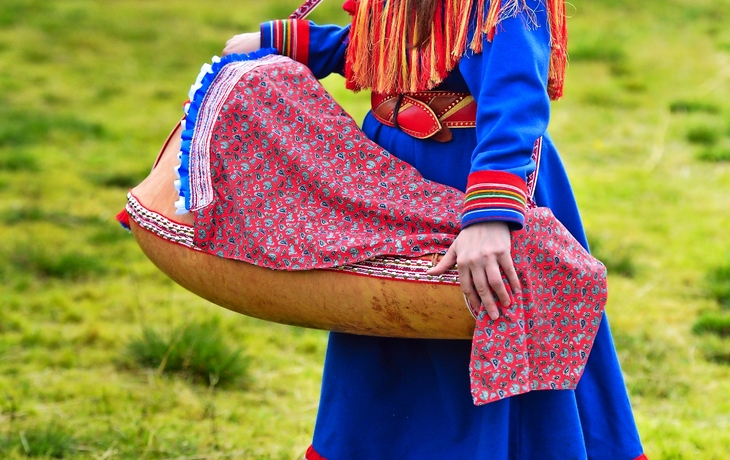 Nord-Norwegen, eine traditionell gekleidete samische Frau mit einer Wiege