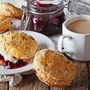 Scones mit Marmelade und Tee mit Milch auf dem Tisch. horizontal